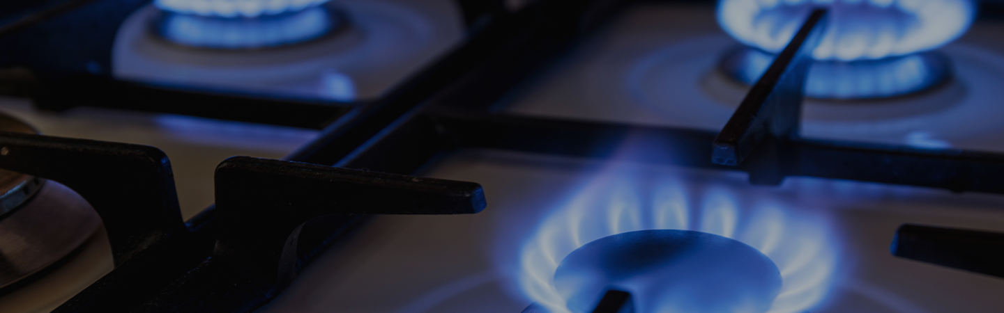 Close up of a multiple gas hobs turned on, burning a blue flame.