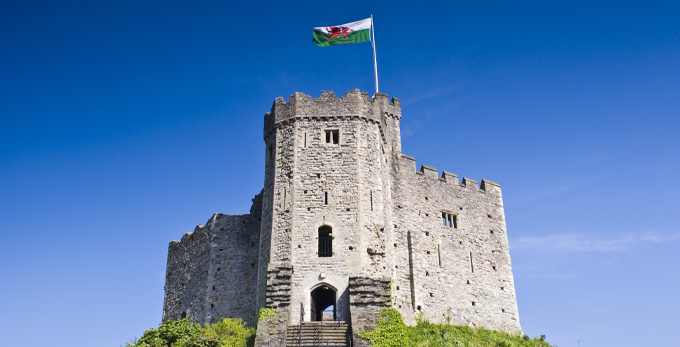 Wales, Cardiff Castle situated within the beautiful Parklands, in the heart of the city. With the Welsh flag moving in the wind on a sunny day.